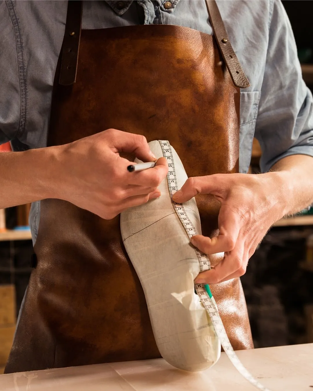 MARITZA atelier — craftsman measuring a shoe last with a tape measure, precision at every step