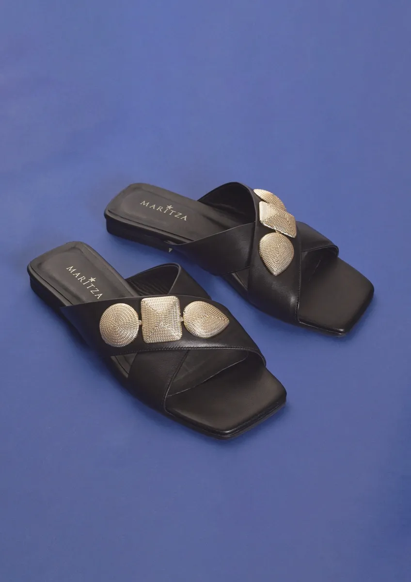 MARITZA black leather crossover slides, flat, with three textured gold ornaments across the strap